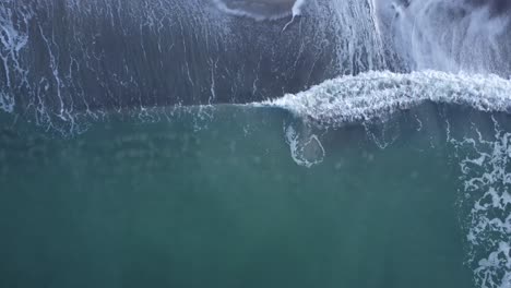 Von-Oben-Nach-Unten-Drohnenaufnahmen-Von-Wellen,-Die-An-Einem-Strand-Zusammenbrechen