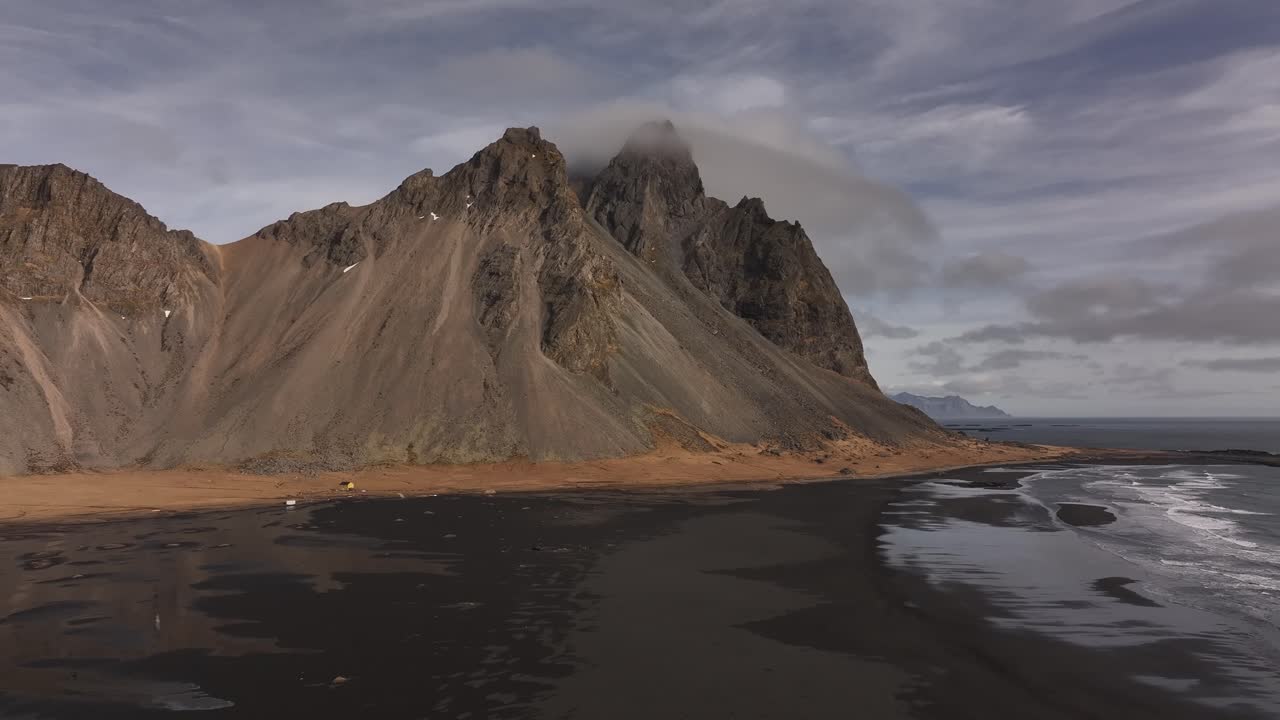 Atlantic waves roll onto Stokksnes’ black sand beach beneath cloud-shrouded Vestrahorn. Iceland
