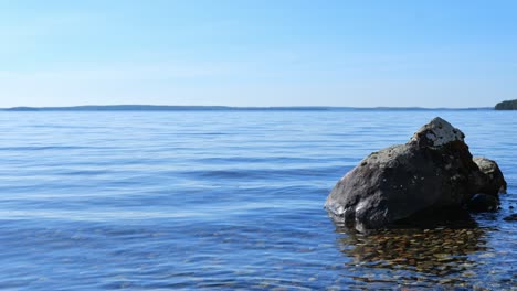 Ruhige-Landschaft-Mit-Ruhigem-Wasser,-Das-Am-Ufer-Winkt