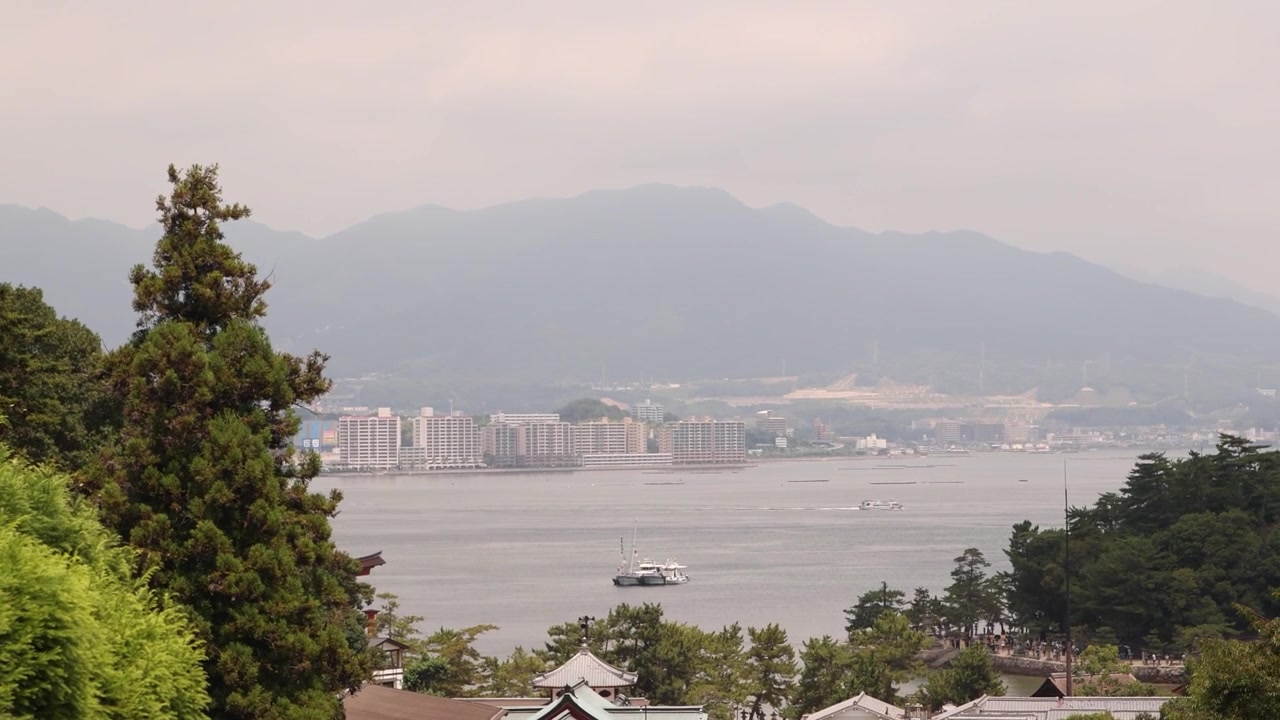 Vista panoramica elevata che si affaccia sulla lussureggiante costa boscosa e sulle calme acque dell'oceano da una collina durante il tradizionale Festival Kangen Sai sull'isola di Miyajima, Hiroshima, Giappone