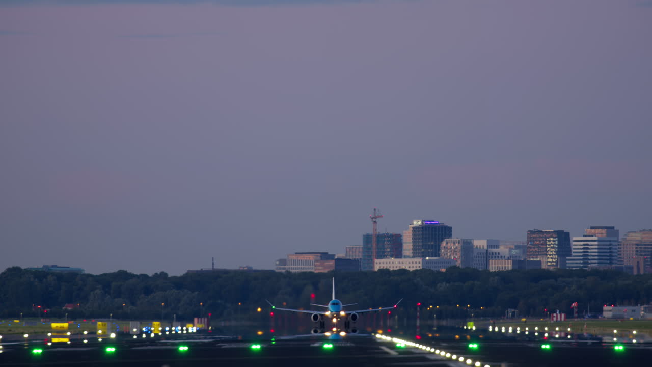 해가 지는 동안 도시 공항에 착륙하는 비행기