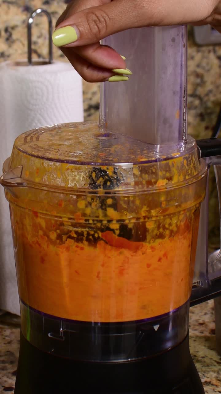 Video verticale della lavorazione di peperoncini rossi in un frullatore da cucina, a fuoco