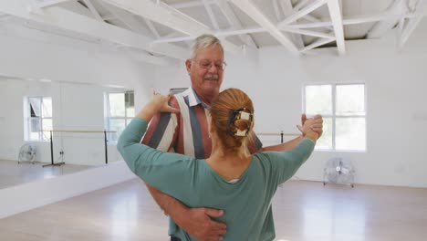caucasian senior couple spending time together in a ballroom and dancing