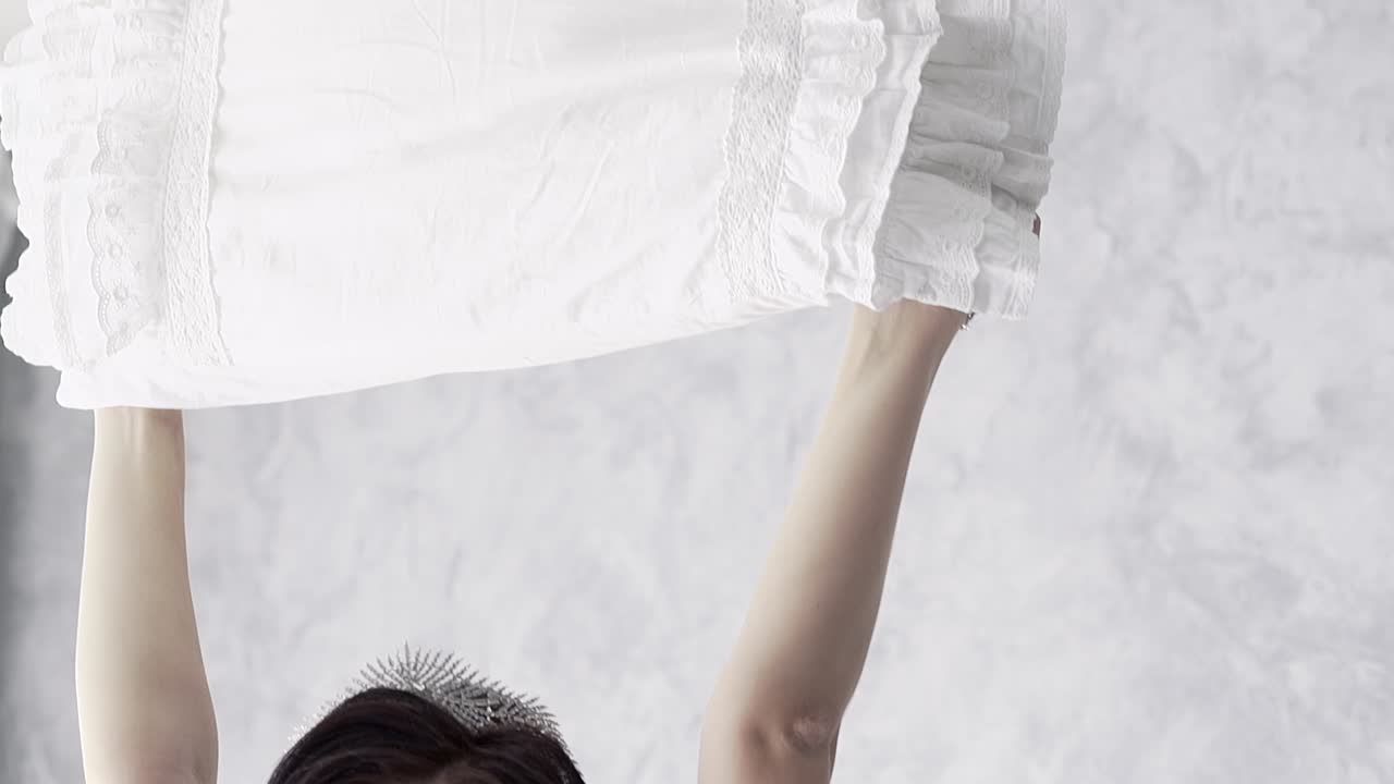 레이시 드레싱을 입은 신부가 사틴 베개를 들고 있습니다.