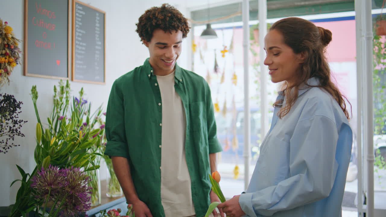 los enamorados sonrientes compran composiciones de flores en la tienda de decoración de floristería de plantas.