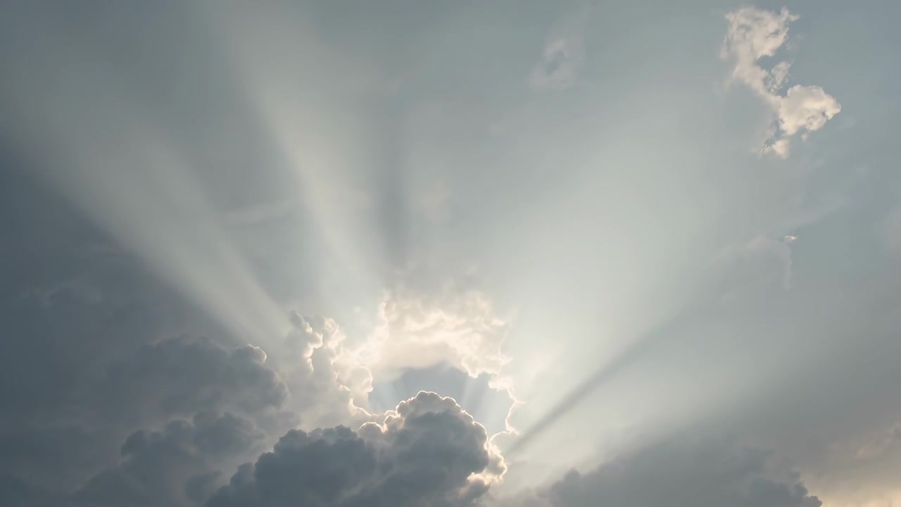 Controluce che rischiara un'imponente nuvola cumuliforme, formando un'apertura circolare e raggi di sole che si irradiano nel cielo.