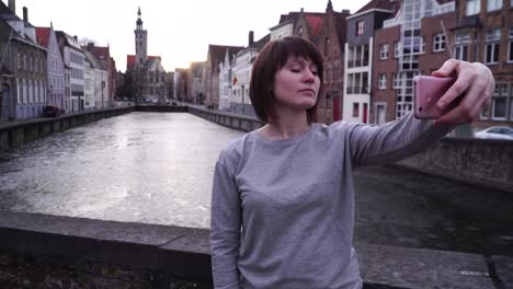 girl tourist makes selfi on a smartphone on a background of the city of bruges belgium