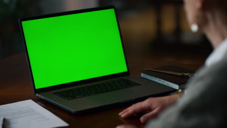 portátil de pantalla verde con una mujer mayor haciendo una llamada de video en casa