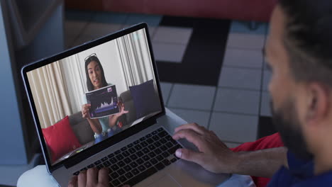 hombre afroamericano haciendo una videollamada con una colega de oficina en una computadora portátil en casa