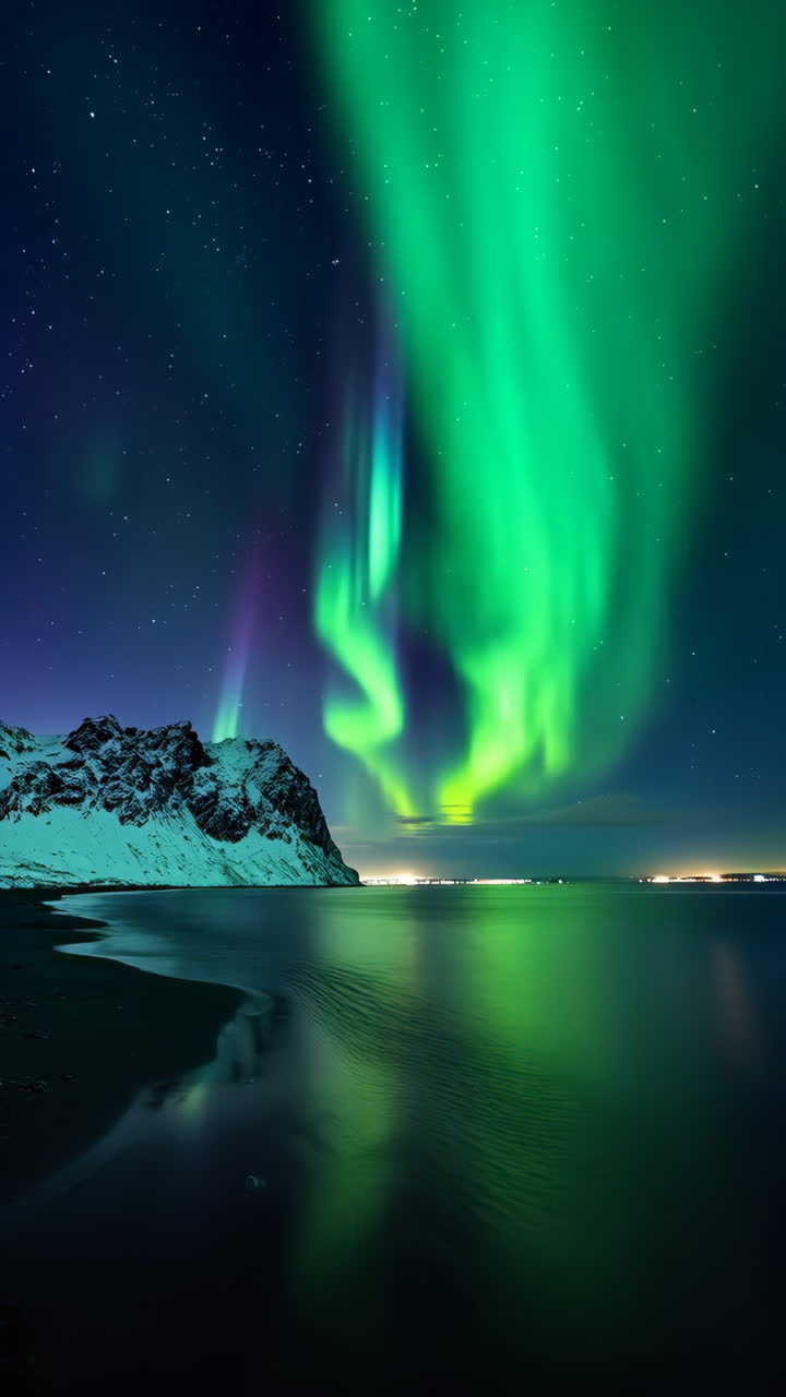 Spectacular Northern Lights Reflecting Over Snowy Mountains and Water