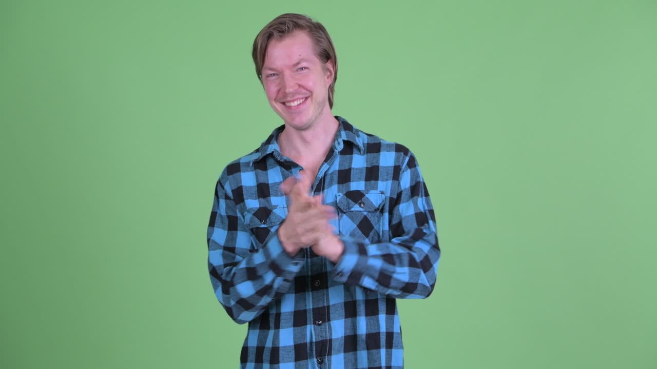 녹색 스튜디오 배경 에 찍힌 백인 남자 의 초상화 가 미소 짓고 박수를 치고 있다