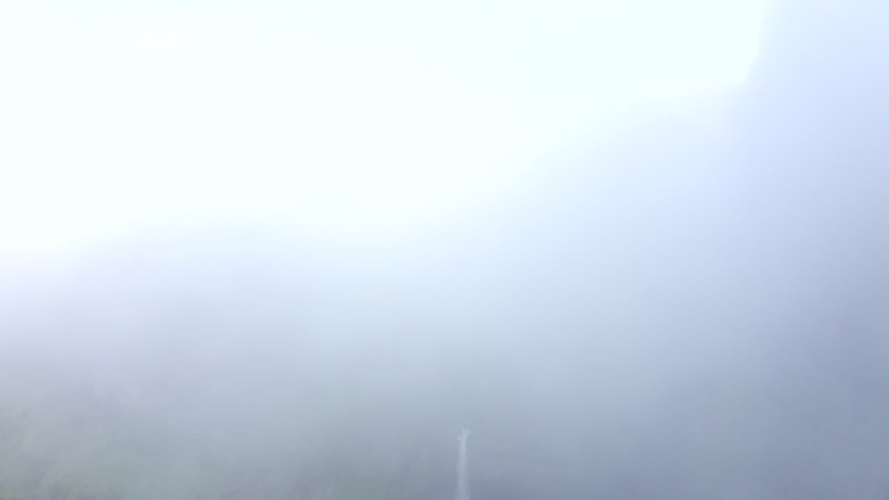 Drone footage of dramatic Hangandifoss waterfall with drone disappearing into white foggy, clouds, to white screen (good for white transition) in Iceland