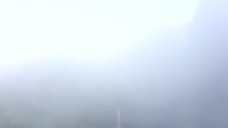 drone footage of dramatic hangandifoss waterfall with drone disappearing into white foggy, clouds, to white screen (good for white transition) in iceland