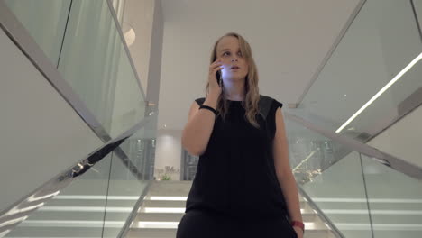 A-young-woman-talking-to-a-smartphone-while-going-downstairs