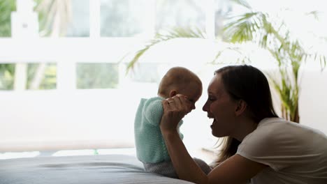 Joyful-excited-mom-helping-baby-daughter-to-sit-up