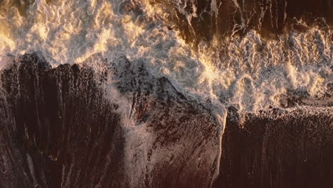 slow motion descending aerial view of ocean waves at magic hour