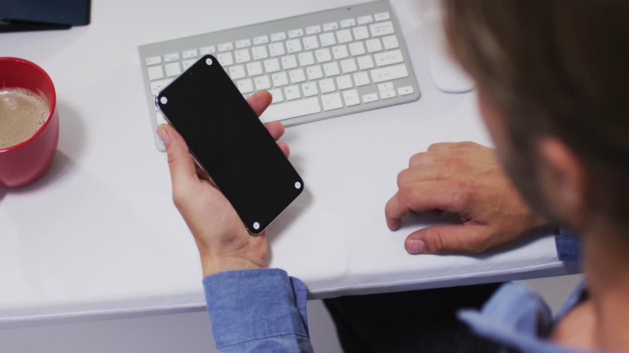 hombre de negocios caucásico que tiene un video en el escritorio usando un teléfono inteligente en el escritorio en la oficina