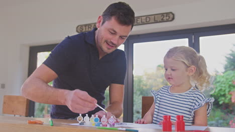 Padre-E-Hija-Divirtiéndose-En-Casa-Sentados-En-La-Mesa-Y-Pintando-Decoración-Juntos---Filmados-En-Cámara-Lenta