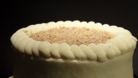 detail shot close up of carrot cake with creme cover and nuts in a turn table black background isolated delicious healthy vegetable sweet