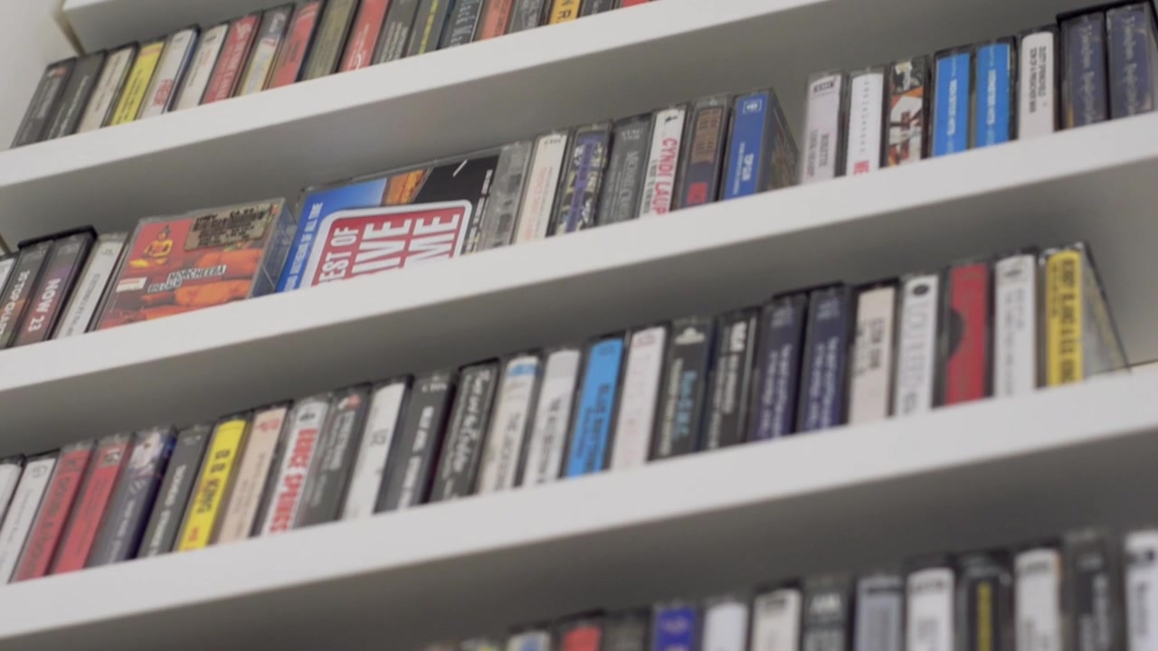 Panoramica verso il basso su scaffali di audiocassette retrò organizzate | Vecchia tecnologia | Girato in HD a 24 fps cinematografici