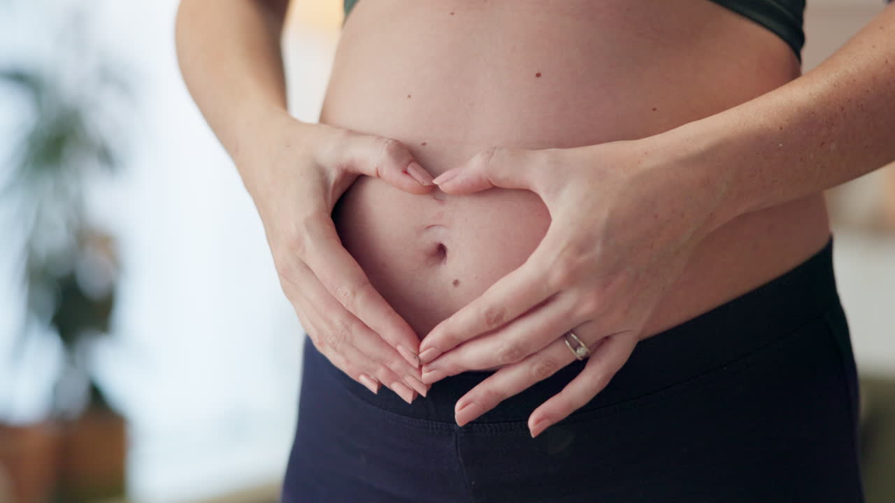 Uma mulher grávida fazendo um coração na barriga.