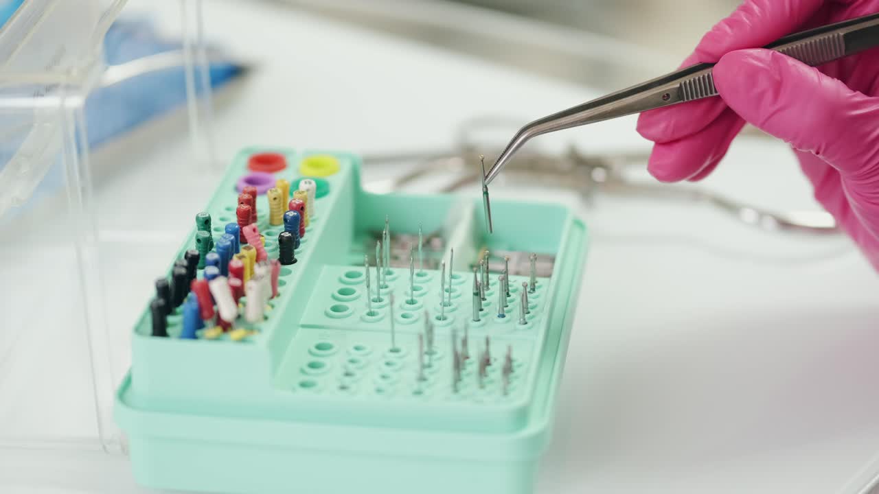el dentista preciso elige la broca dental adecuada de la caja del organizador con una pinza
