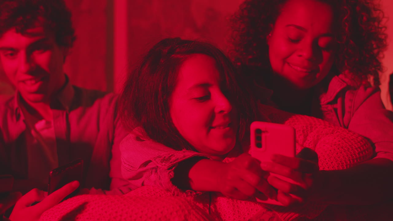 chica acostada en las rodillas de sus amigos y mirando la pantalla del teléfono