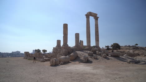 a man walking in front of ruins of temple of hercules in ancient amman citadel, jordan