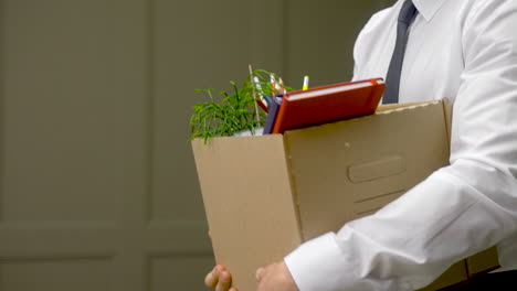 close up of a unrecognizable employee leaving the office with his personal stuff in a box 1