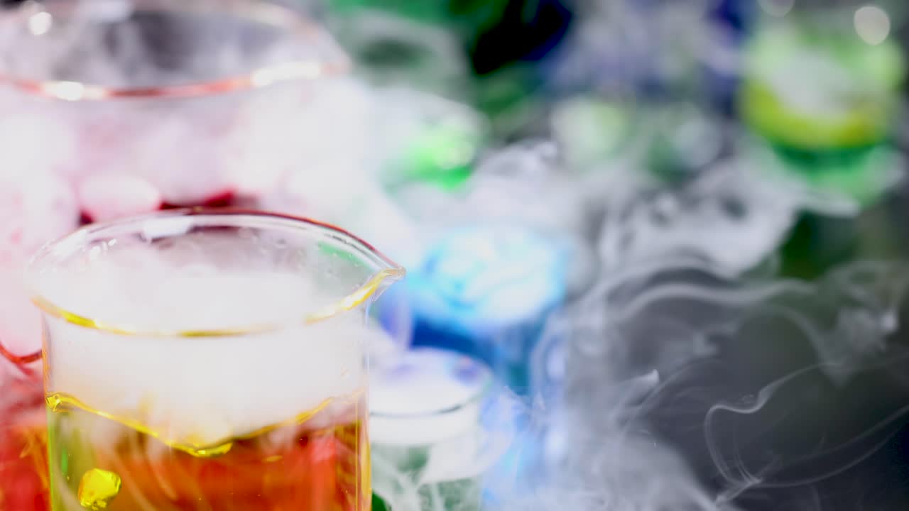 다채로운 액체와 증폭하는 연기가 있는 컵