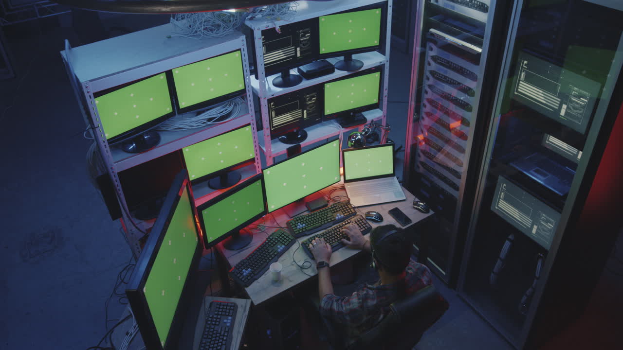 Hacker Using Computer with Multiple Monitors full Shot of a Young Hacker Using a Computer with Multiple Monitors