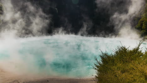 tilt down shot of steam rising up to sky from boiling inferno crater lake during sunny day in new zealand