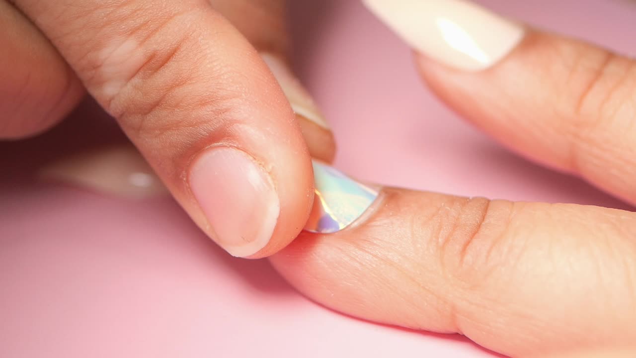 Close-up of hands applying iridescent nail art