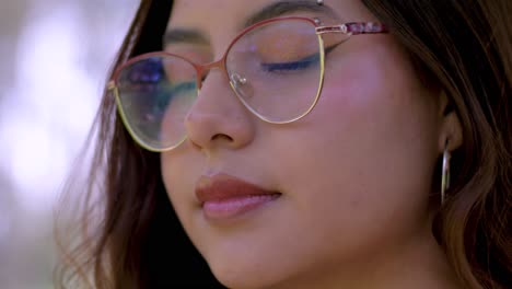 fotografía en primer plano de una mujer con gafas y cabello abierto, dirigiéndose hacia la cámara con una mirada cautivadora, que irradia confianza y atractivo
