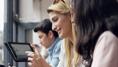 young woman friends using digital tablet touchscreen showing vacation photographs