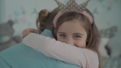 retrato de una pequeña hija vestida de princesa abrazando a su papá en casa