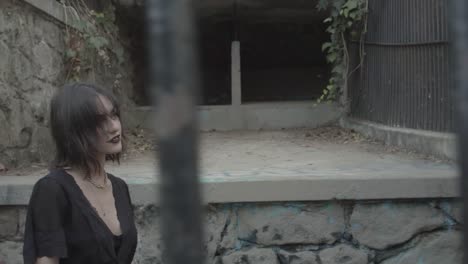 gothic girl in black dress behind prison cell bars looking at camera with smile