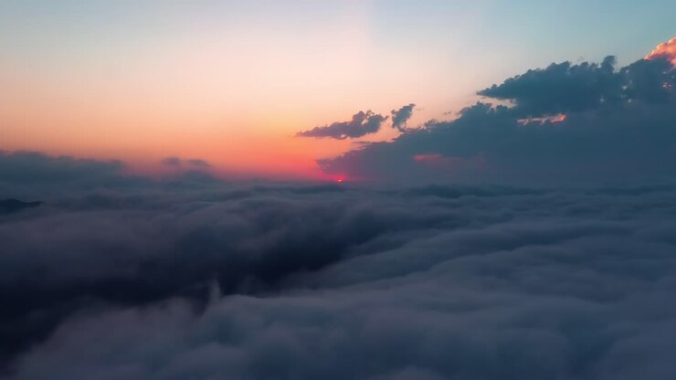 Volando sopra le nuvole con il sole calante. Sfondo di cielo colorato all'alba o al tramonto.