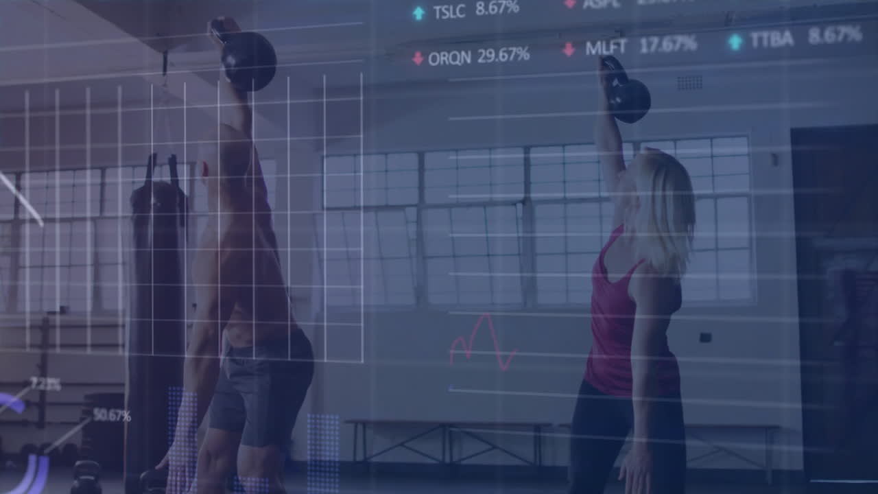 Mid adult man and woman lifting kettlebells in gym studio, displaying finance charts overlaying