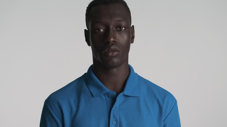 Hombre afroamericano serio sobre fondo gris.