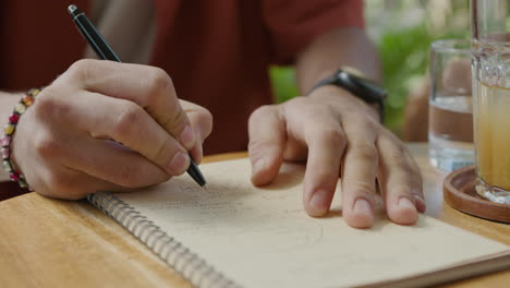 man taking notes while speaking on the phone in cafe