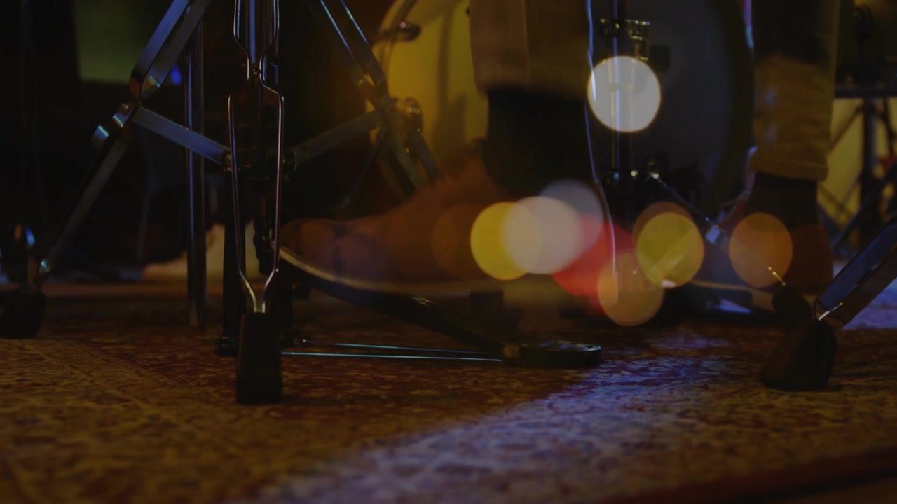 Il piede del batterista inizia a sollevare il tallone, premendo il pedale della grancassa per il ritmo musicale, con un effetto bokeh caldo sul piede.