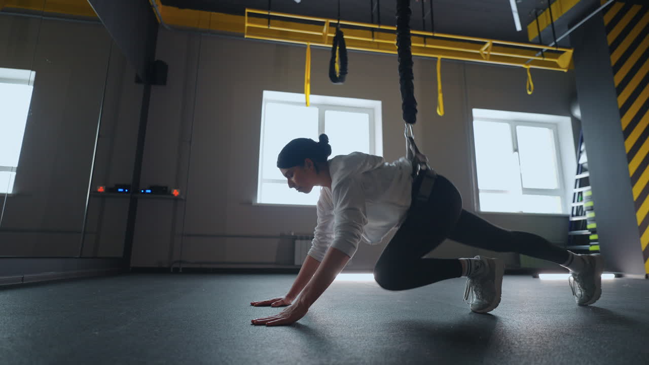 una mujer atlética está practicando un sistema de fitness moderno con trx para entrenar su cuerpo.