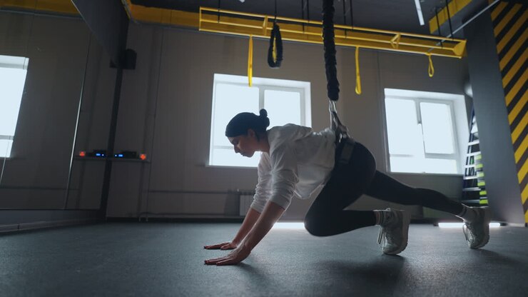 athletic woman is practicing modern fitness system with TRX for trainingher body