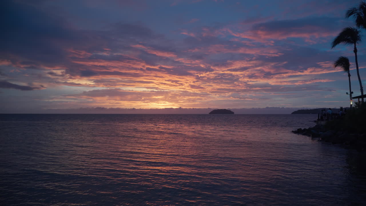 Sunset Over Sea - Majestic Pink Purple Colorful Sundown Sky and Sun Setting Behind Water Horizon, Purplish Sunlight Reflections in Low Tide Waves Rolling Towards Tanjung Aru Beach on Cloudy Evening
