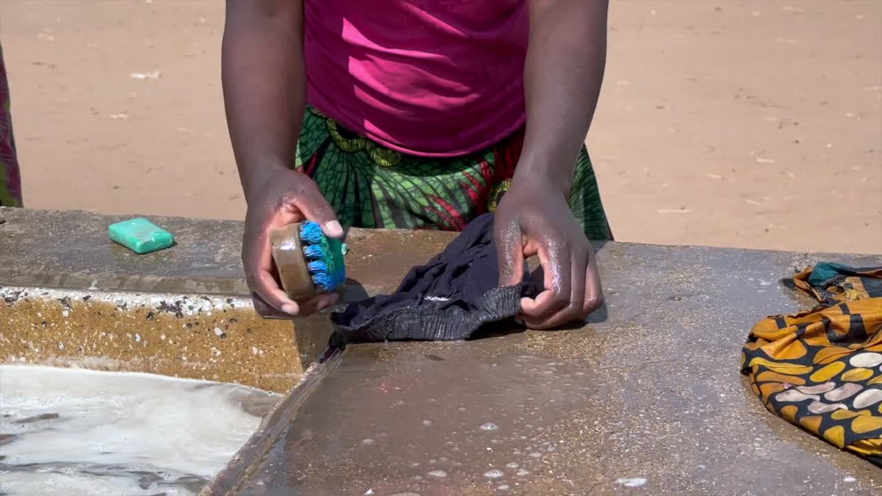 Woman hands washing clothes at a well in the middle of a village, Malawi.