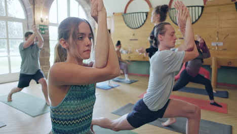 Yoga class practicing warrior pose with eagle arms