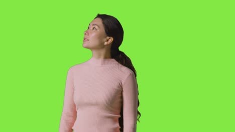 Studio-Portrait-Of-Woman-Turning-To-Look-All-Around-Frame-Against-Green-Screen