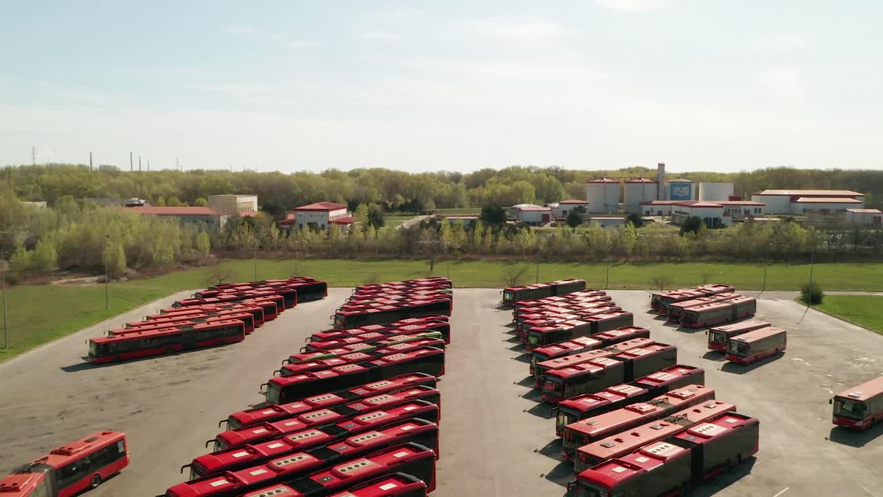 Aerial view of a parking lot for public transportation buses. One red  bus is driving away. Industrial background on transportation theme.