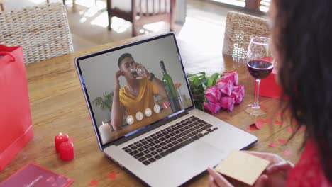 hombre biracial con vino haciendo una videollamada del día de san valentín en una computadora portátil